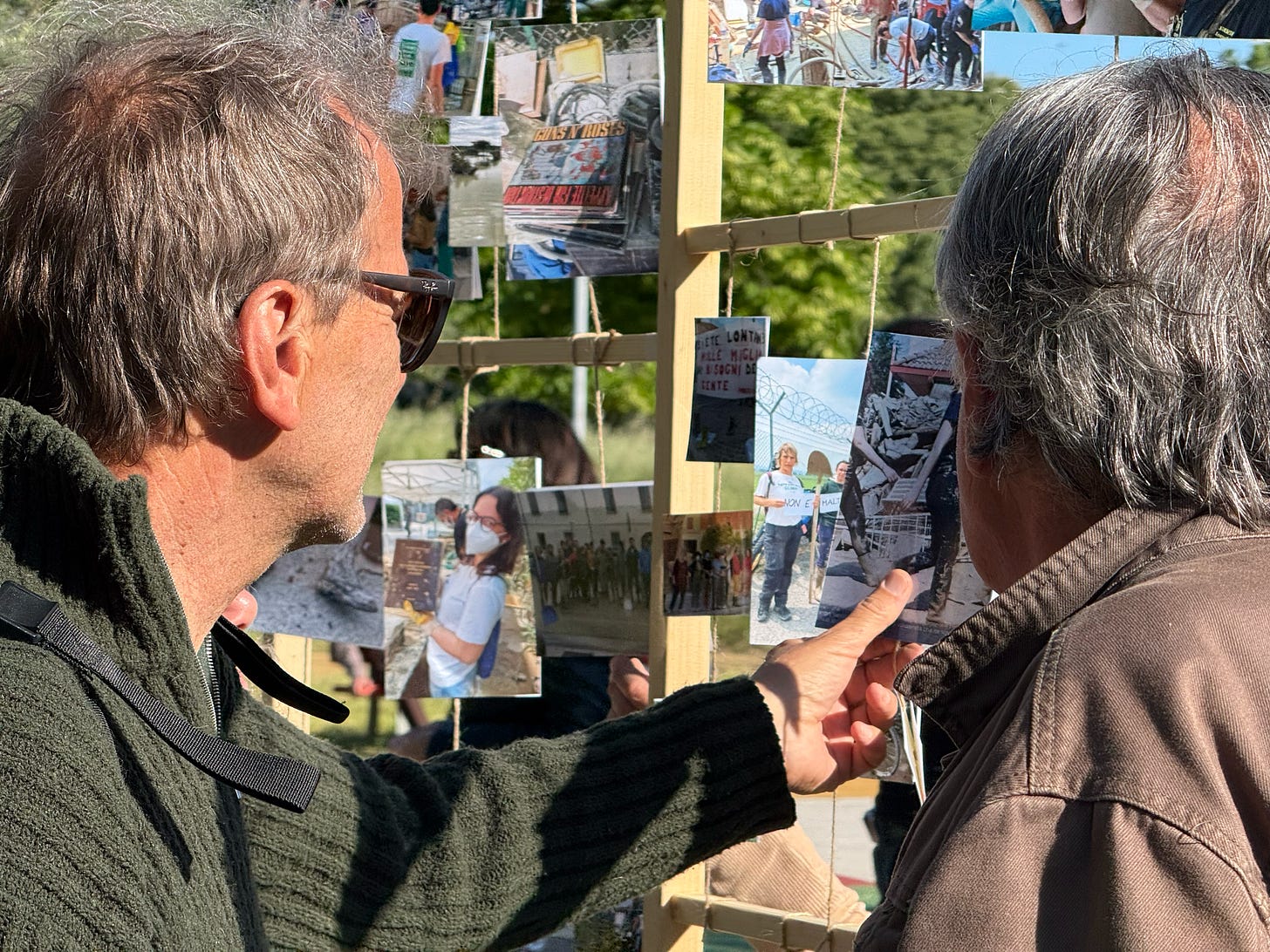 Due partecipanti osservano le fotografie esposte alla mostra collettiva dopo l’alluvione in Romagna, durante la giornata del 24 maggio 2025. Le immagini raccontano la memoria viva della comunità e il legame tra disastro e resilienza locale.