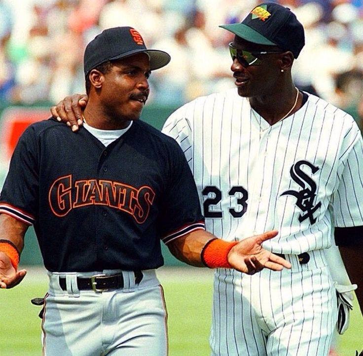 This may contain: two baseball players standing next to each other in front of a crowd on a field