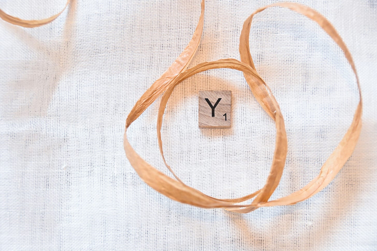 image of the Scrabble letter "Y" in the center of a swirtl of vanilla colored raffia