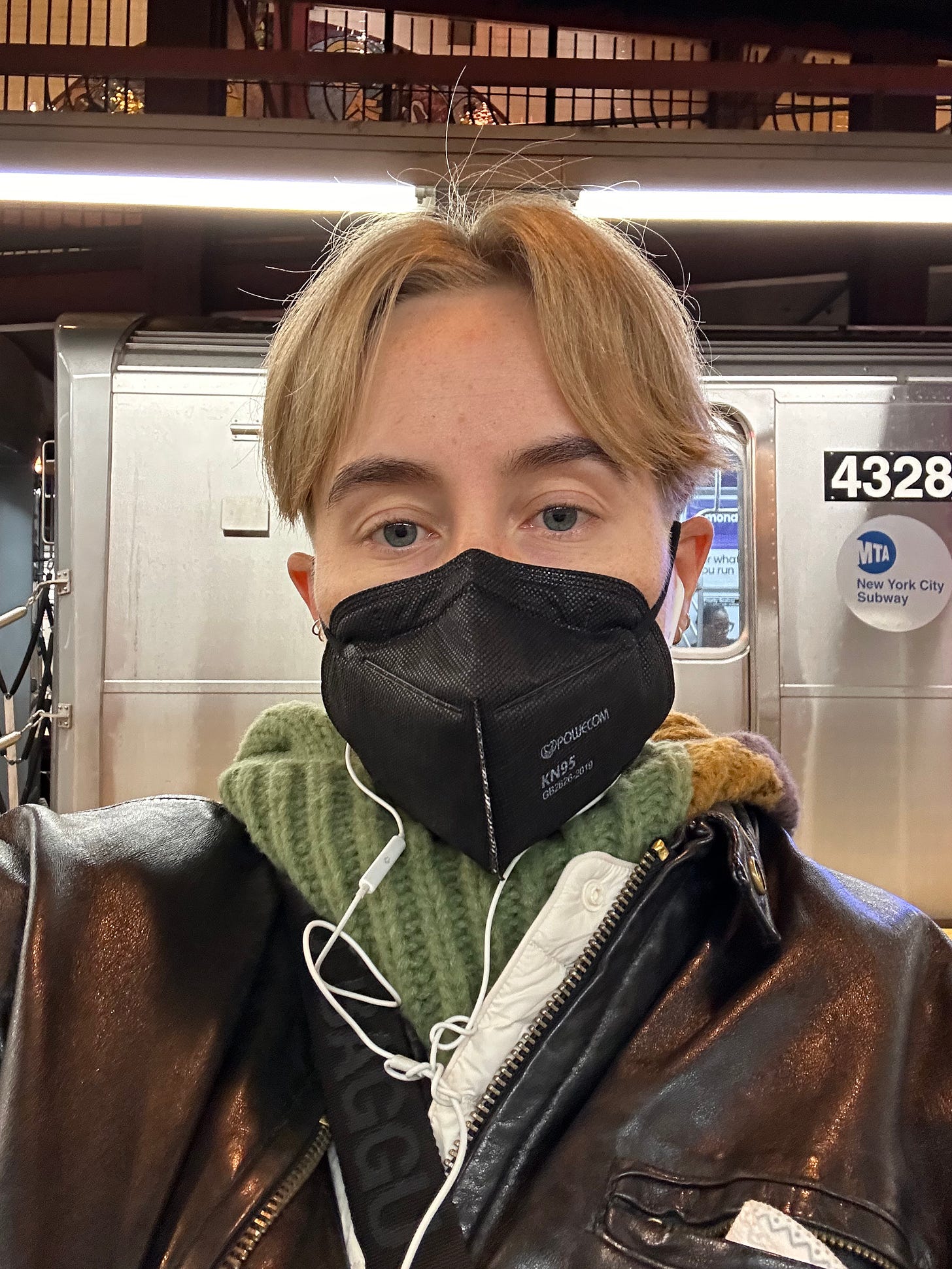 selfie of Fi in a mask with the nyc subway behind them