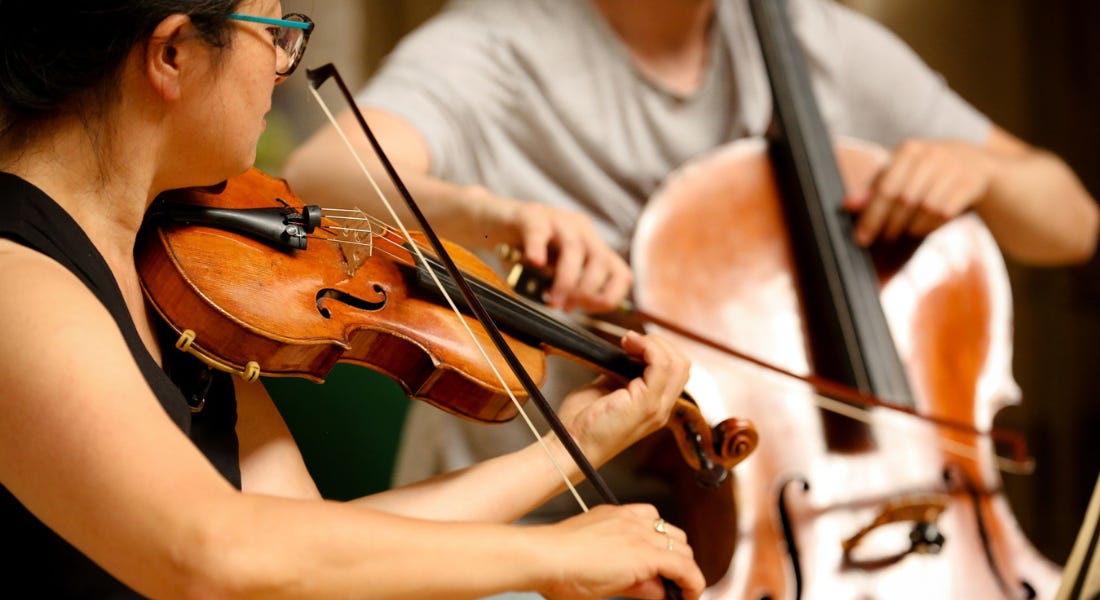 Two people playing violins and cellos
