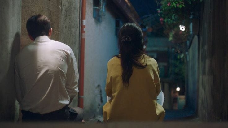 This may contain: the man and woman are walking down the narrow alleyway in the city at night This may contain: the man and woman are walking down the narrow alleyway in the city at night