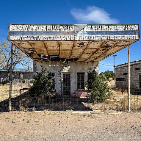 a decrepit gas station, vintage advertising sign and old car