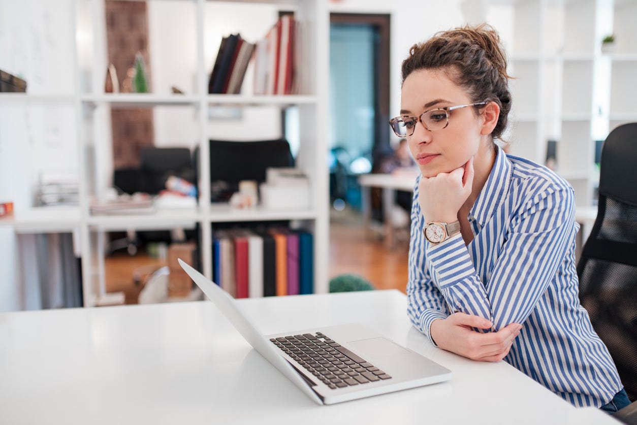 Young professional woman sitting at a desk and looking at her laptop.