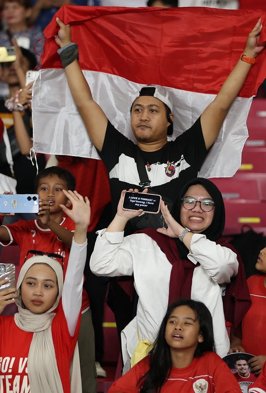 Indonesian football fans cheer and wave the national flag during an ASEAN football match, showing support for their team at the stadium. Indonesian football fans cheer and wave the national flag during an ASEAN football match, showing support for their team at the stadium.