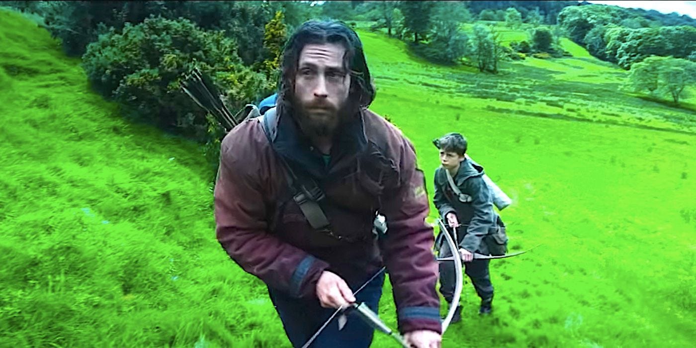 Aaron Taylor-Johnson's Jamie wielding a bow and walking in a field with a boy from 28 Years Later trailer.