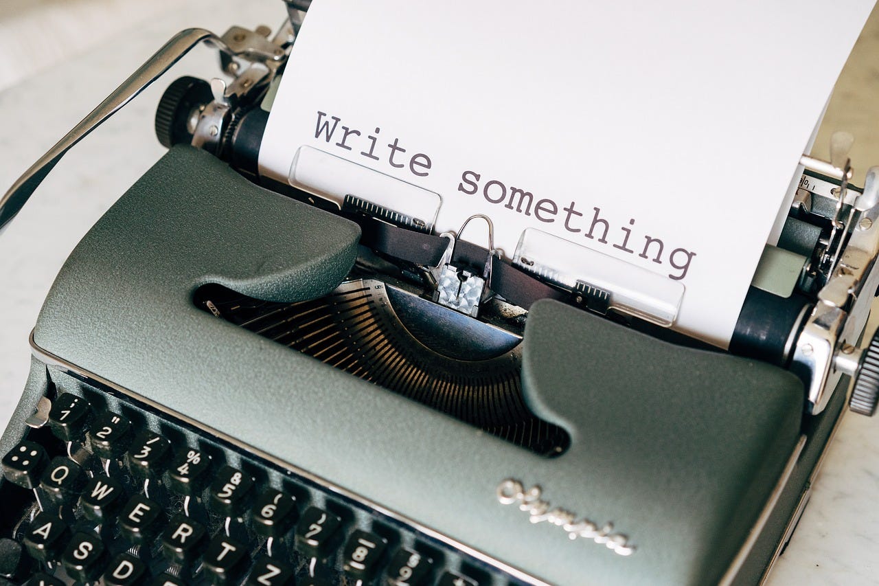 Typewriter with a sheet of paper saying, "Write something"