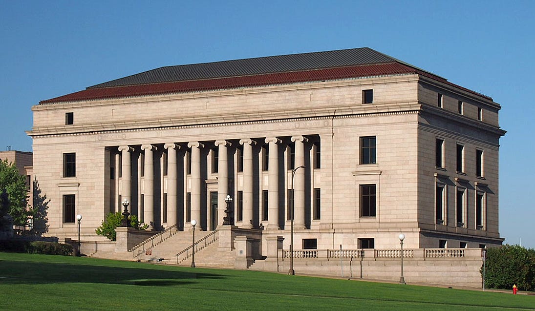 An exterior view of the columned Minnesota Justice Center. Blue sky, green grass. 