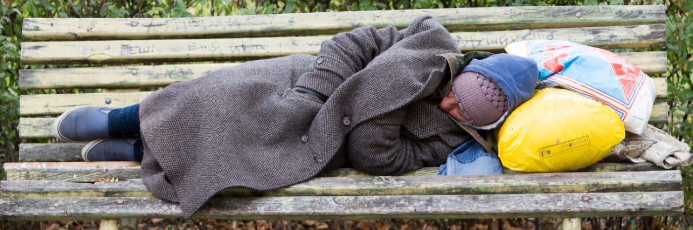 A homeless person sleeping on a bench. A homeless person sleeping on a bench.