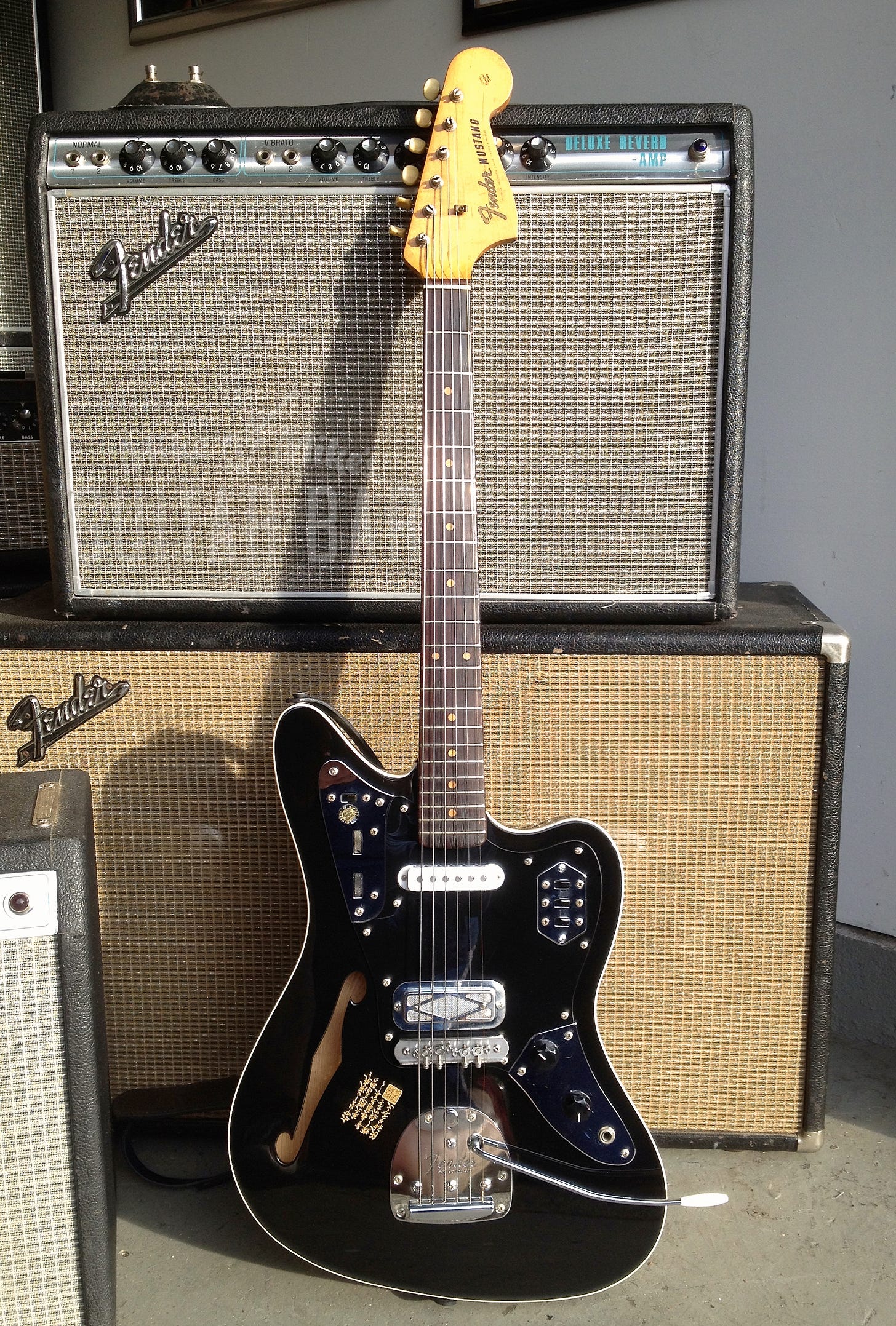A sleek Japanese Jaguar Thinline electric guitar with a black finish and chrome hardware.