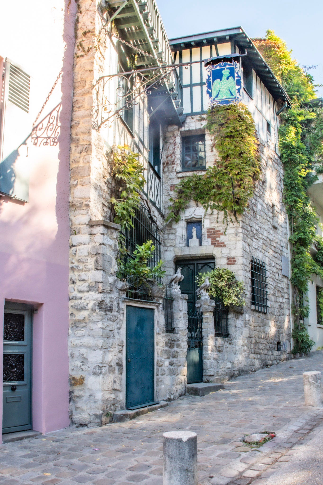 Historic stone house on Rue de l'Abreuvoir in Montmartre, featuring ivy-covered walls, timber framing and traditional Parisian architecture.