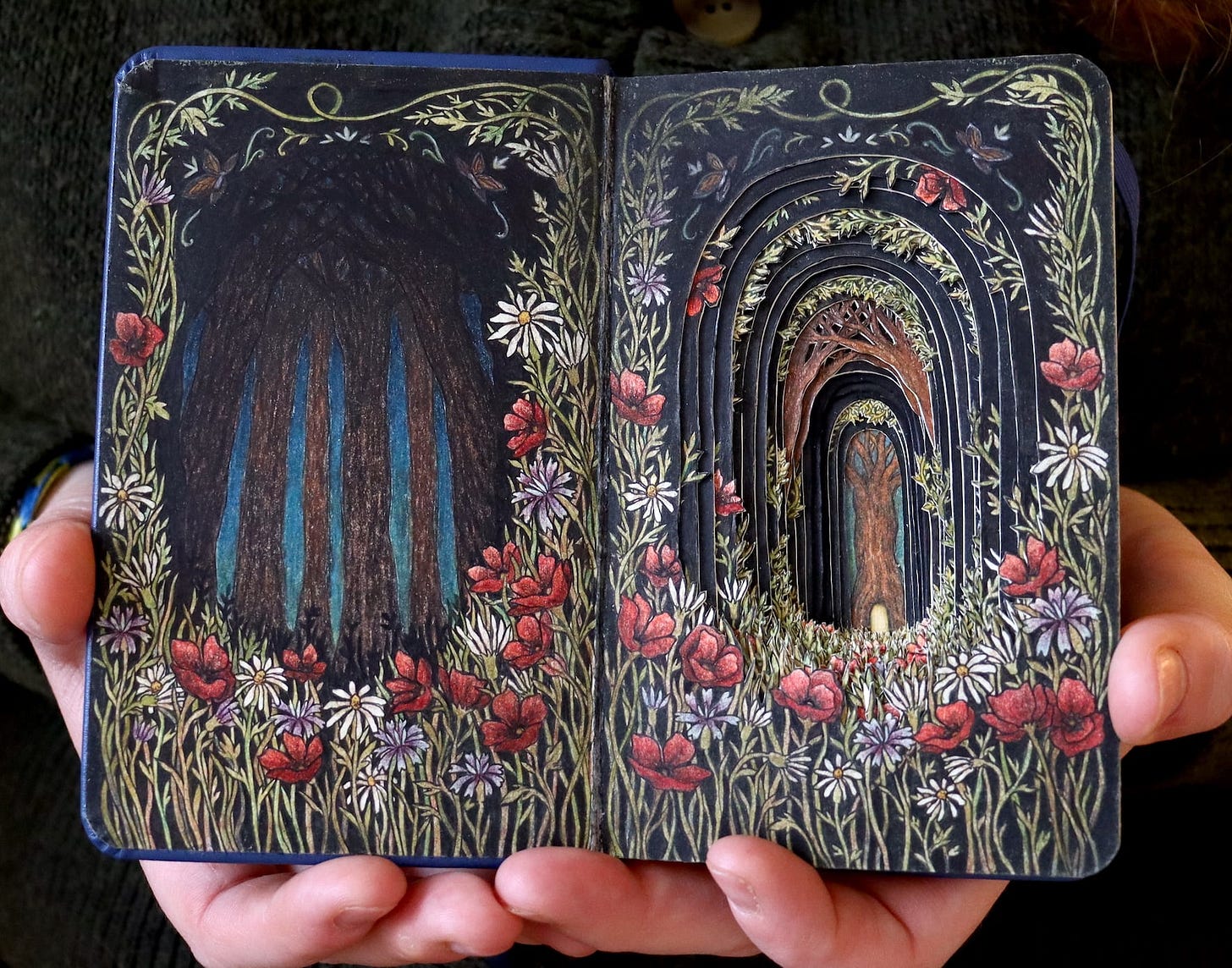 A photo of a book opened to reveal a cut-paper forest scene A photo of a book opened to reveal a cut-paper forest scene