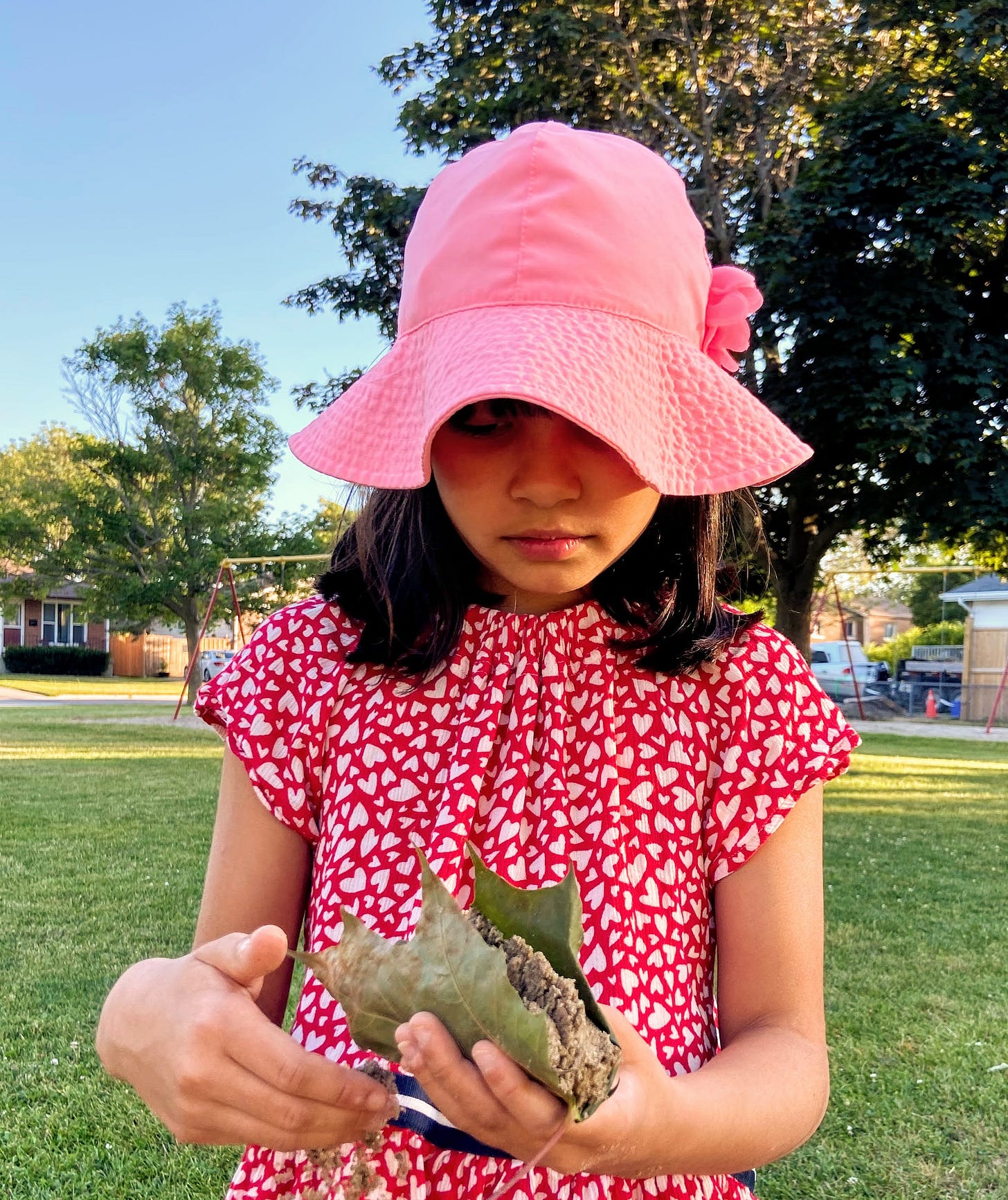 Girl holding leaf with sand bundled inside