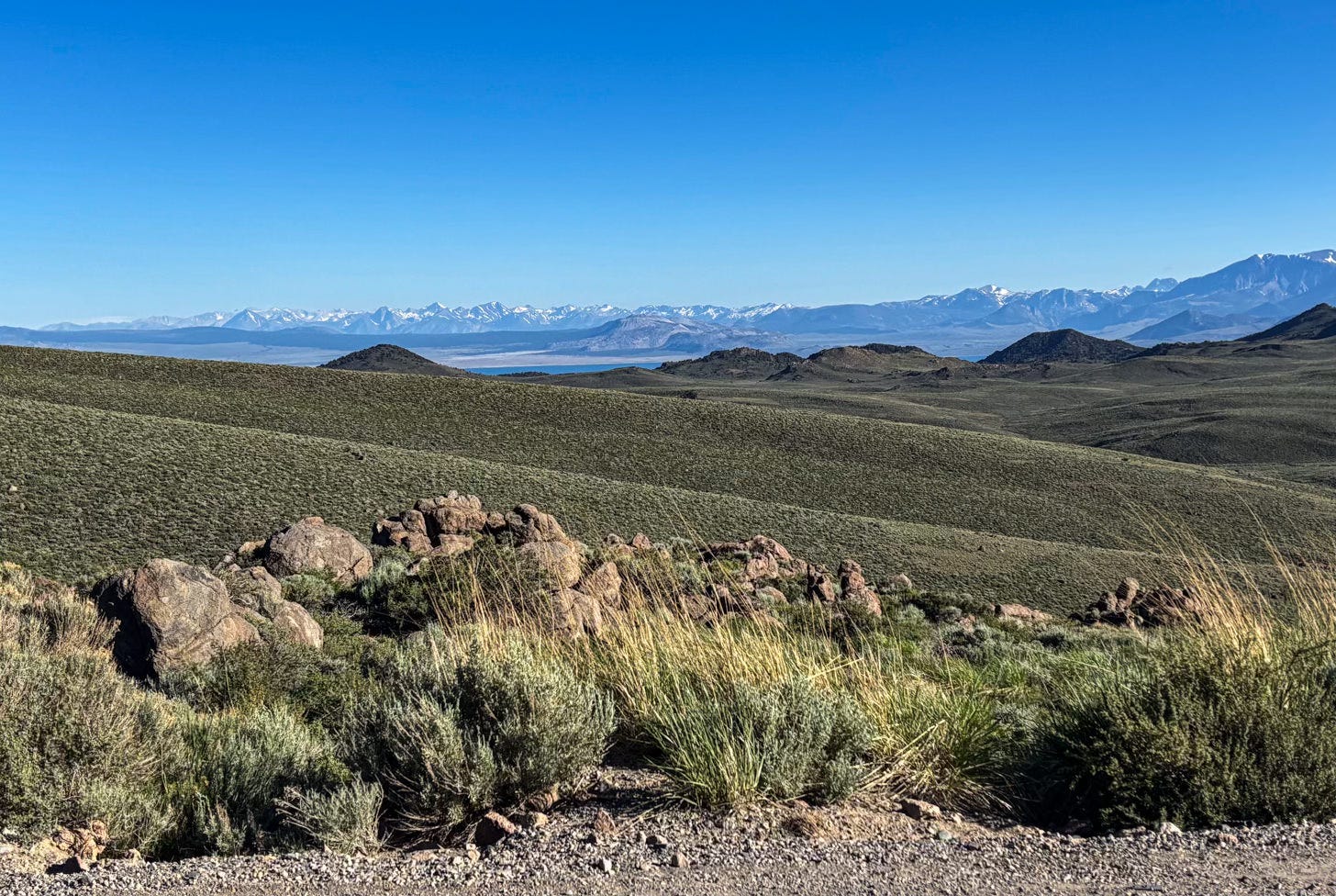 view of hills with snow capped peaks in distance