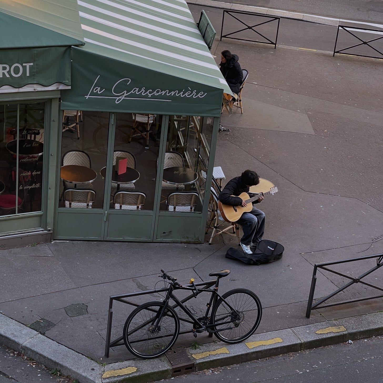 Young boy playing guitar outside of a Paris bistro Young boy playing guitar outside of a Paris bistro