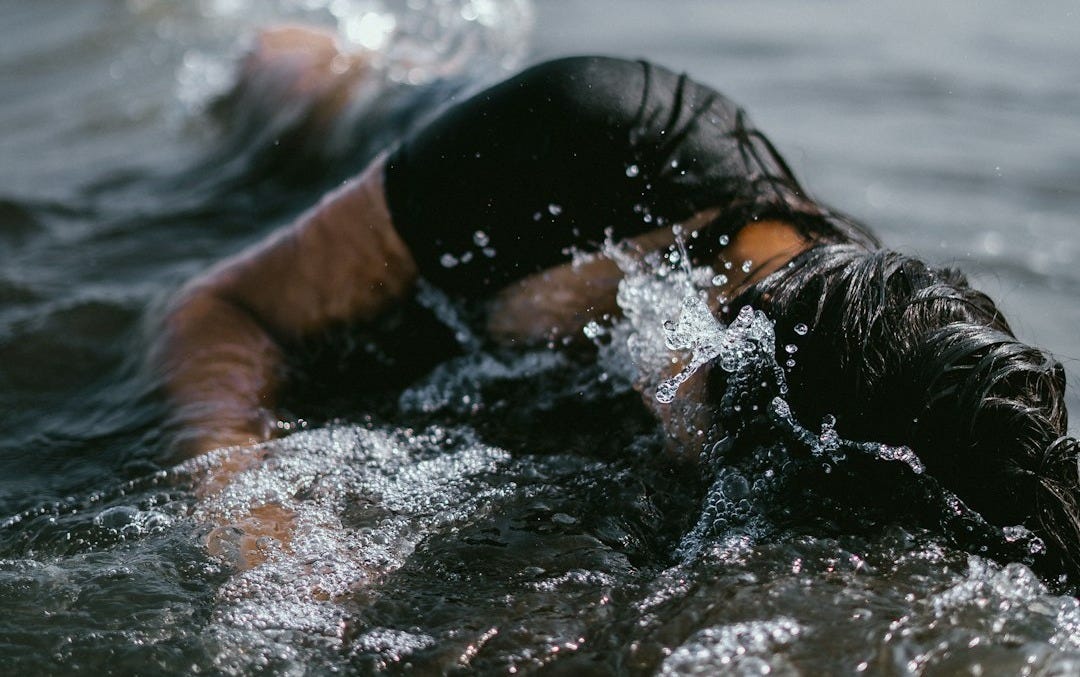 woman half submerge on body of water