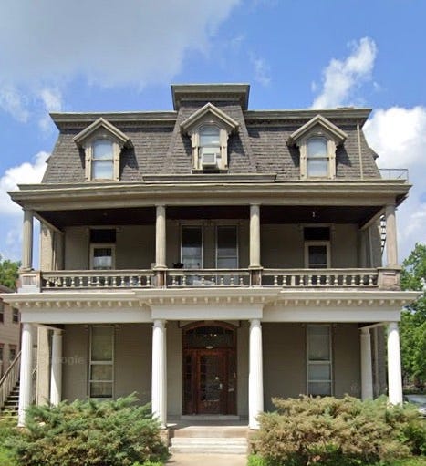 Photo of a 3- story, very symmetrical house. A sidewalk leads to a door in the center; there are windows on each side. Columns on the first floor support a porch on the second story. The 3rd story has a mansard roof with 3 gabled windows. The house appears to be in good repair but still looks vaguely spooky. Photo of a 3- story, very symmetrical house. A sidewalk leads to a door in the center; there are windows on each side. Columns on the first floor support a porch on the second story. The 3rd story has a mansard roof with 3 gabled windows. The house appears to be in good repair but still looks vaguely spooky.