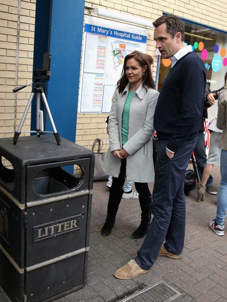 Emily Nash facing a camera placed on a bin standing next to a man Emily Nash facing a camera placed on a bin standing next to a man