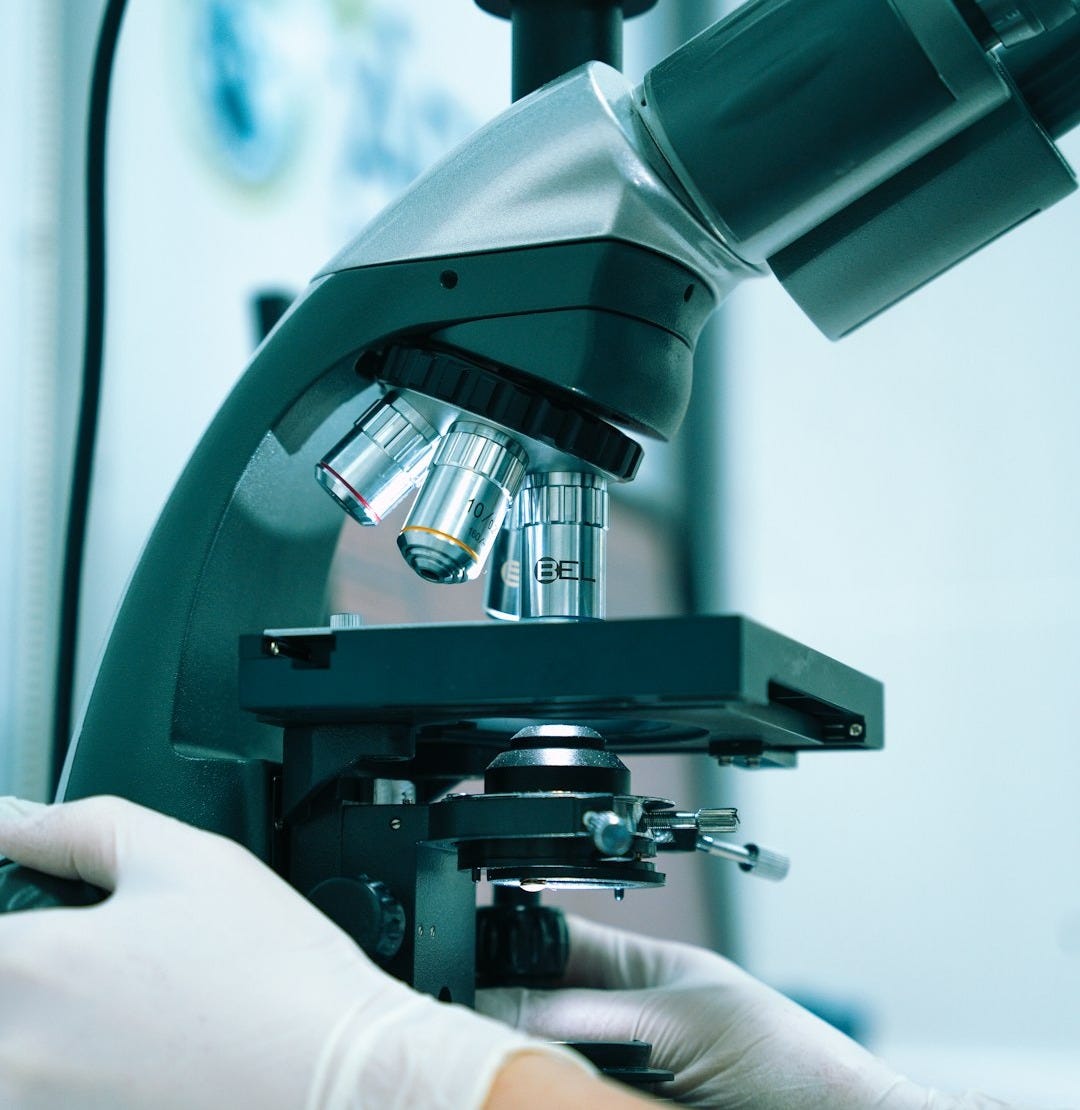 a gloved hand operating a microscope in a laboratory
