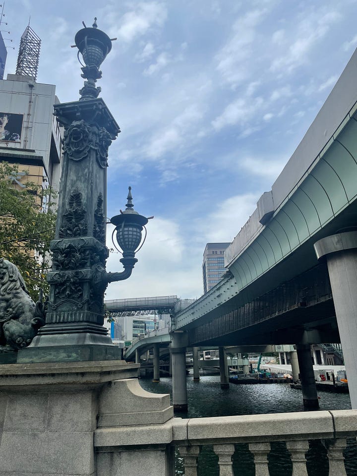 Four photographs of the bridge and the river beneath it, all of which are dominated by the expressway viaducts, which stand on thick concrete pillars dropped haphazardly into the river and fill almost its complete width, putting the bridge and river entirely into shade and blocking much of the sky.