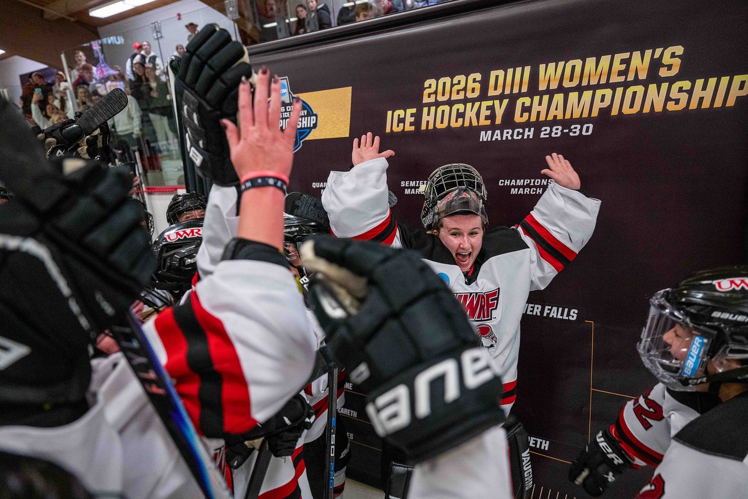 Jordan O'Kane puts her hands in the air as other hockey players celebrate alongside her