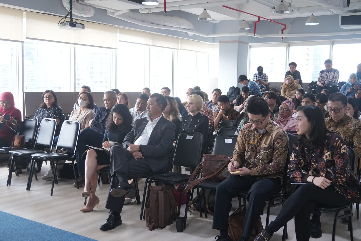 The audience sitting in a room watched and listened carefully to the panelists' speeches.