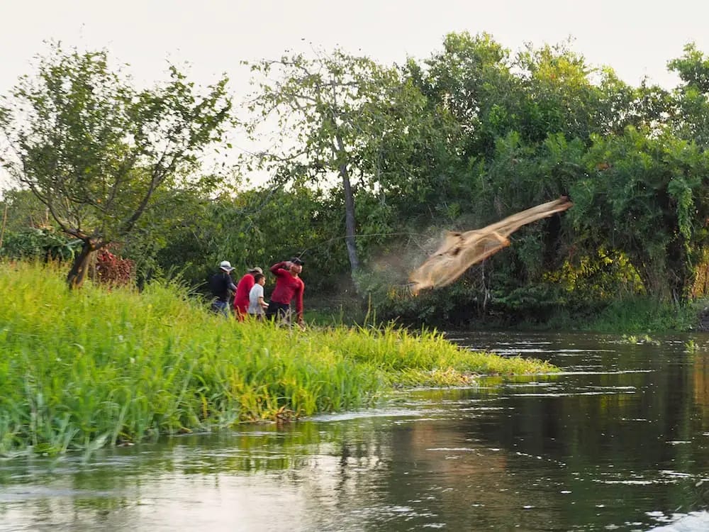 Fishermen throw a net into the river Fishermen throw a net into the river