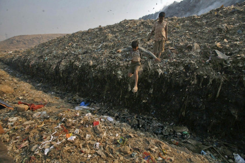 Waste collector Dinesh Mukherjee, 11, watches his friend jump over a puddle of toxic liquid at the Ghazipur landfill in New Delhi November 10, 2011. Photo by Parivartan Sharma/Reuters 