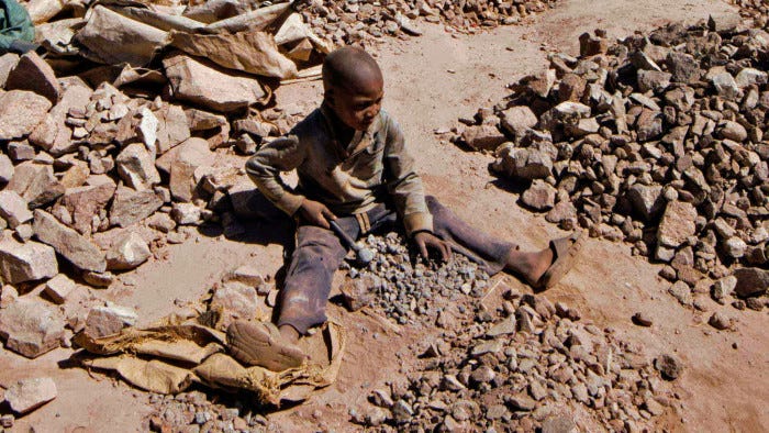 A child breaks rocks extracted from a cobalt mining at a copper mine quarry and cobalt pit in Lubumbashi on May 23, 2016.
The price of copper has fallen heavily, directly impacting workers in the town. / AFP PHOTO / JUNIOR KANNAH