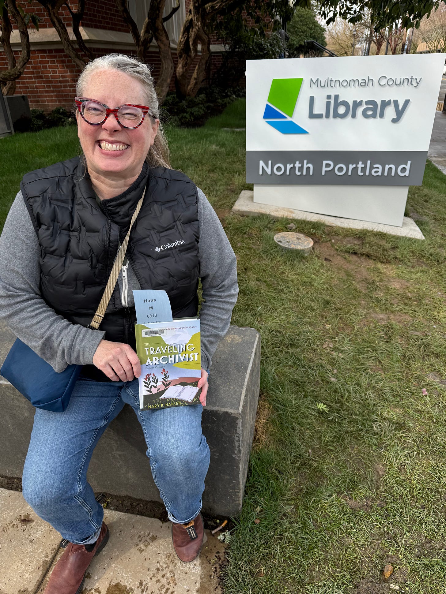 woman holding a book in front of library sign woman holding a book in front of library sign