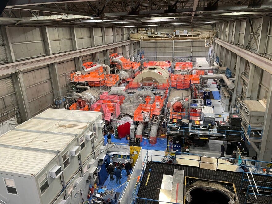 Looking down on the inside of a massive, hangar-like building. The room is filled with metal equipment, including the Palisades turbine, which sits partially dissassembled. Orange netting covers much of the area around the building. Looking down on the inside of a massive, hangar-like building. The room is filled with metal equipment, including the Palisades turbine, which sits partially dissassembled. Orange netting covers much of the area around the building.