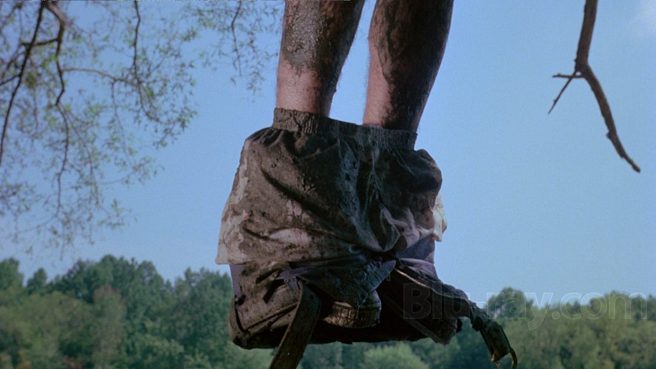 a screen cap from the film I Spit on Your Grave from 1978 in which a man's legs are hanging in the air with their pants around their ankles.