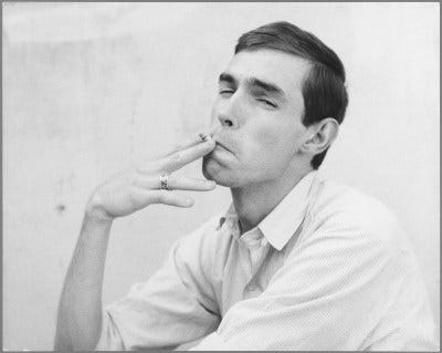 A young man in a button-down shirt smoking.