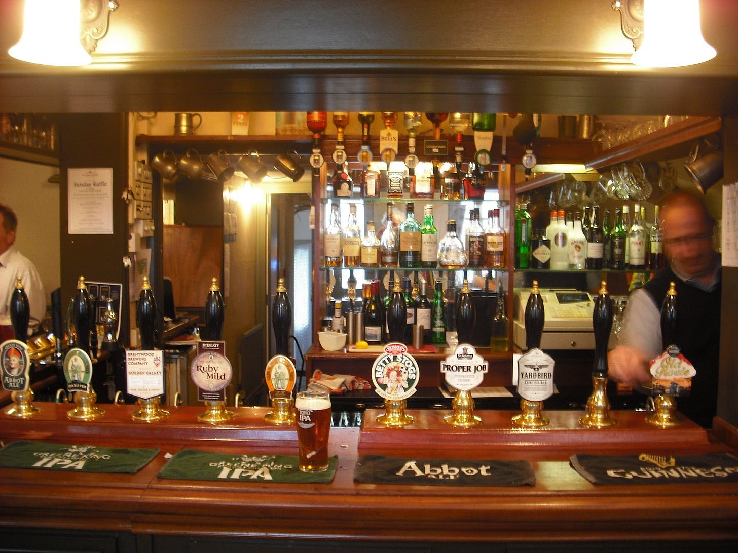 Nine real ale handpumps lined up on a dark wood bar