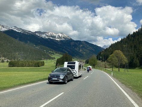 Photo of antique wooden coach and modern camper on a highway.