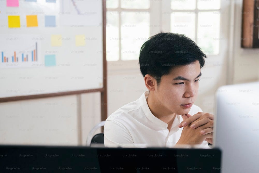 Jovem analista de mercado financeiro que trabalha no escritório e analisa o marketing online em seu computador.
