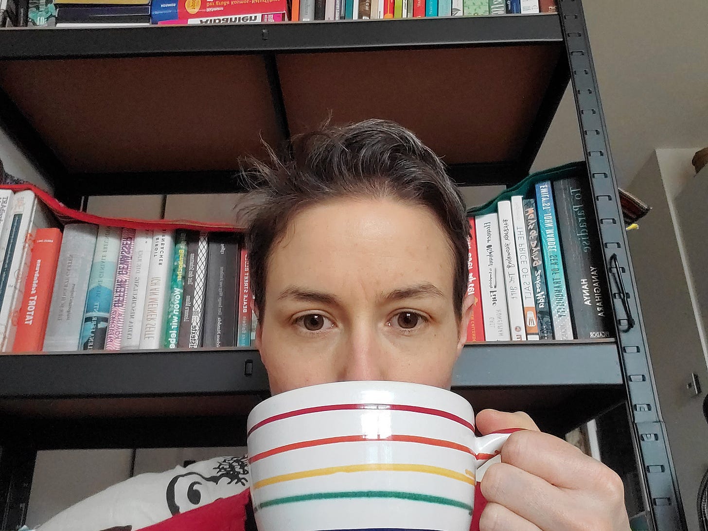The photo shows the author, a white woman with brown hair sitting in front of a bookcase and holding a tea cup in front of her face, covering her mouth. 