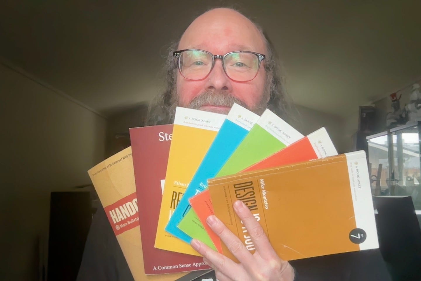 Photo of the author holding books in front of his face, displaying the people who have taught him as a designer and developer