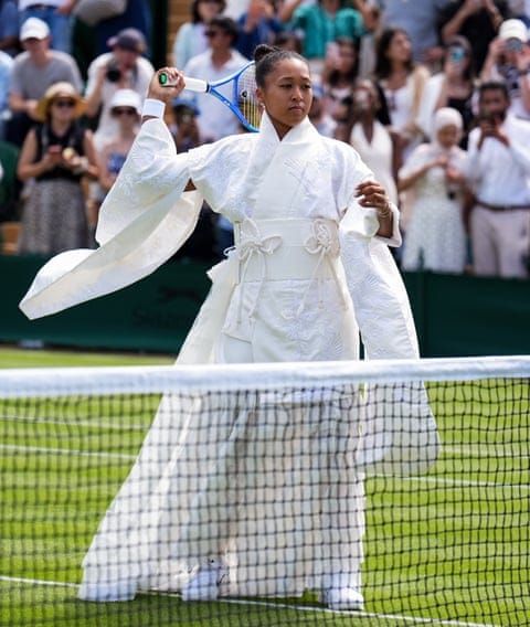 Naomi Osaka practises a serve at the net while wearing her sculptural kimono-inspired creation embroidered with cranes and cherry blossom