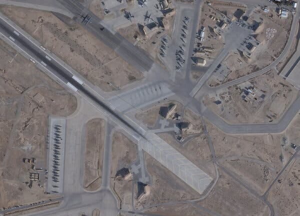 Overhead view of an extensive airfield with numerous gray aircraft parked on paved areas. Tan ground surrounds the runways and several small buildings. Overhead view of an extensive airfield with numerous gray aircraft parked on paved areas. Tan ground surrounds the runways and several small buildings.