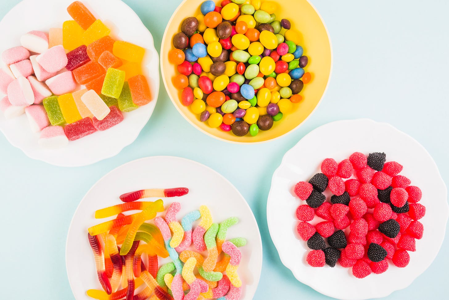 Four bowls of different kinds of sweets and candies.