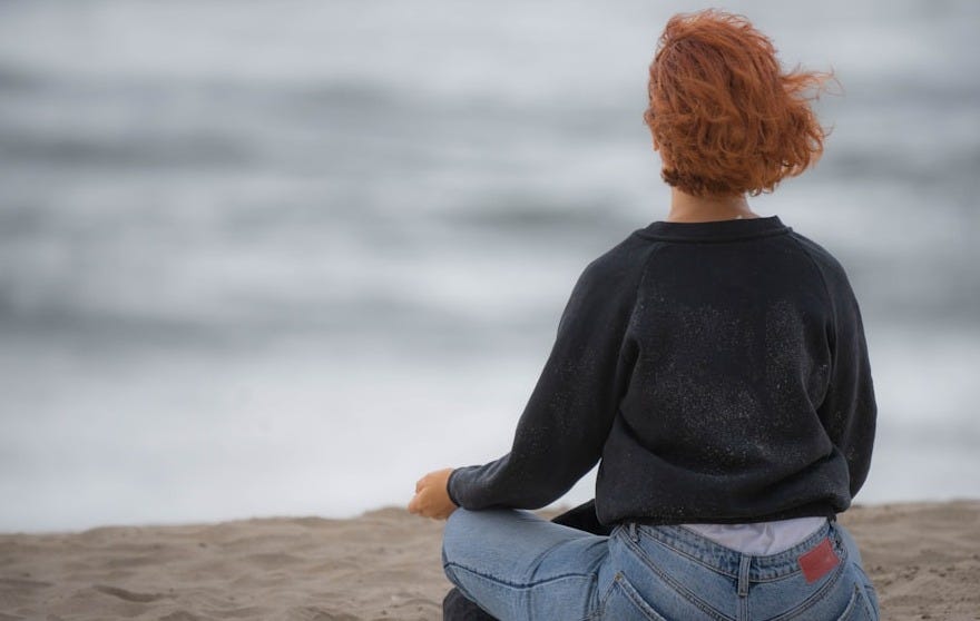 a woman sitting in the sand on the beach a woman sitting in the sand on the beach