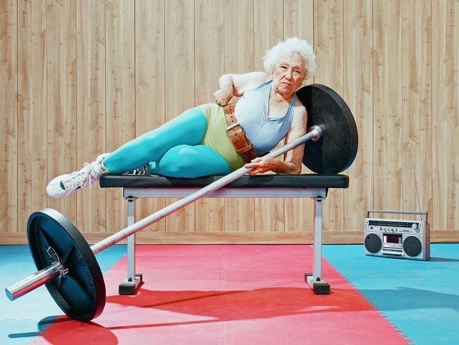 This may contain: an old woman is laying on a bench with a barbell This may contain: an old woman is laying on a bench with a barbell