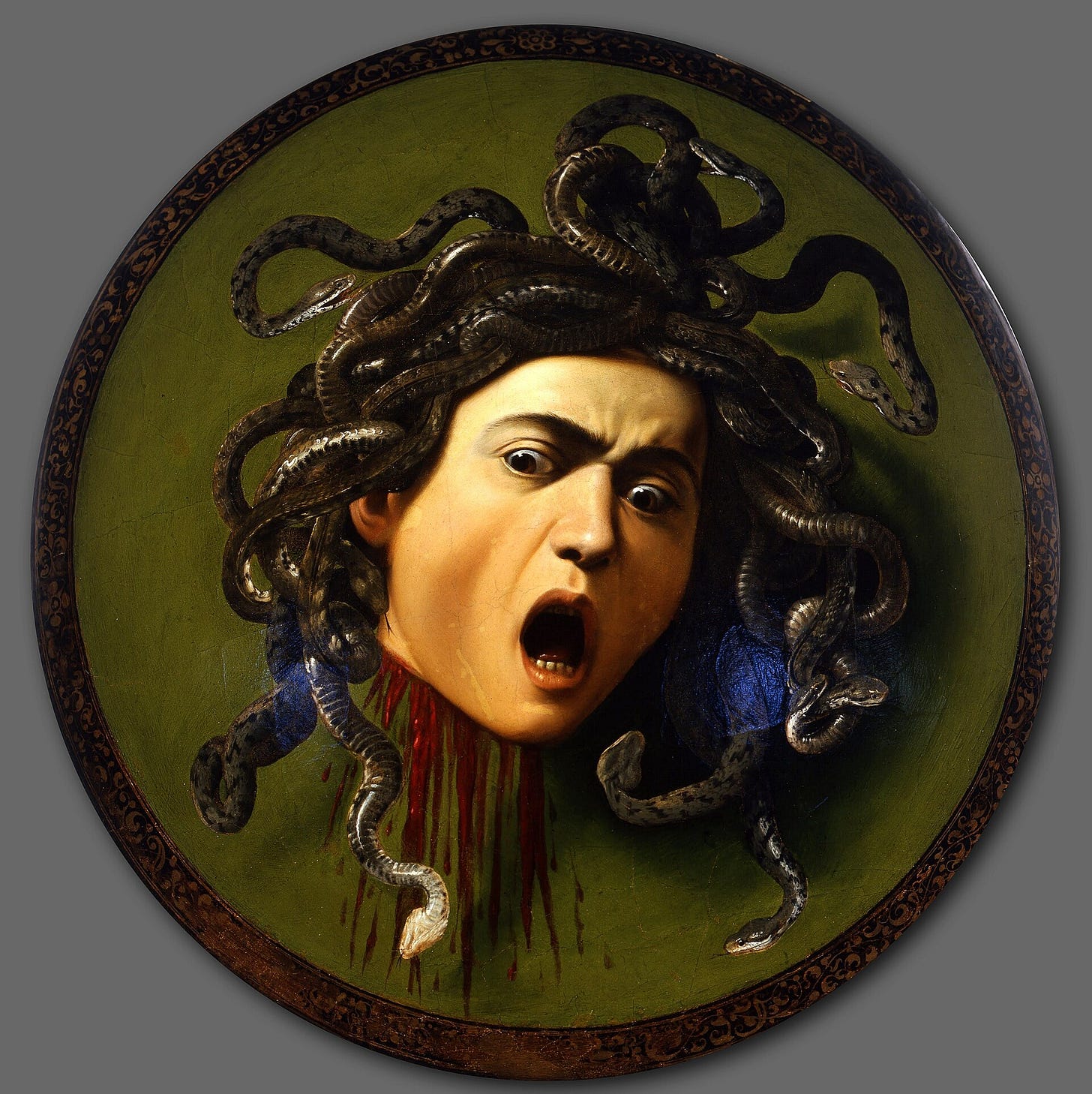 A severed head with a wide-open mouth and a crown of writhing snakes, painted on a round green shield, blood running from the neck.