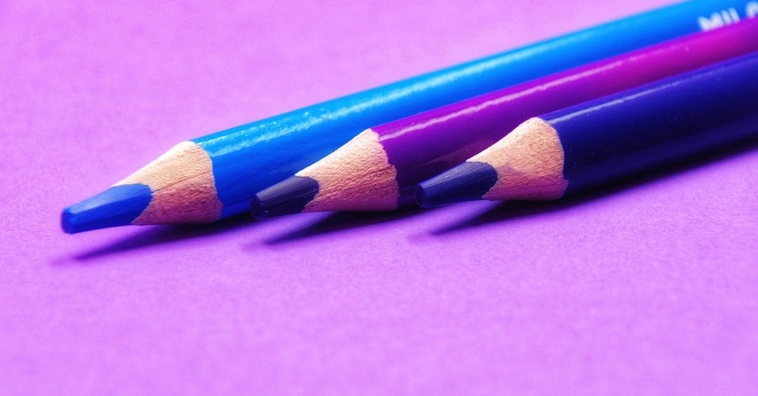 two pencils are sitting side by side on a purple surface