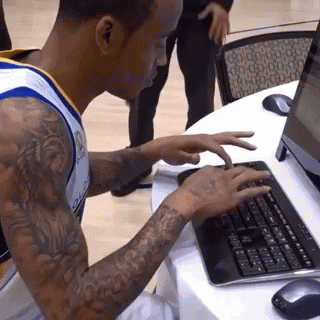 a man with a tattoo on his arm is typing on a computer keyboard