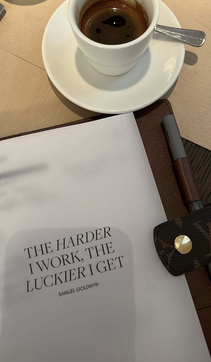This may contain: a cup of coffee sitting on top of a table next to a book and pen