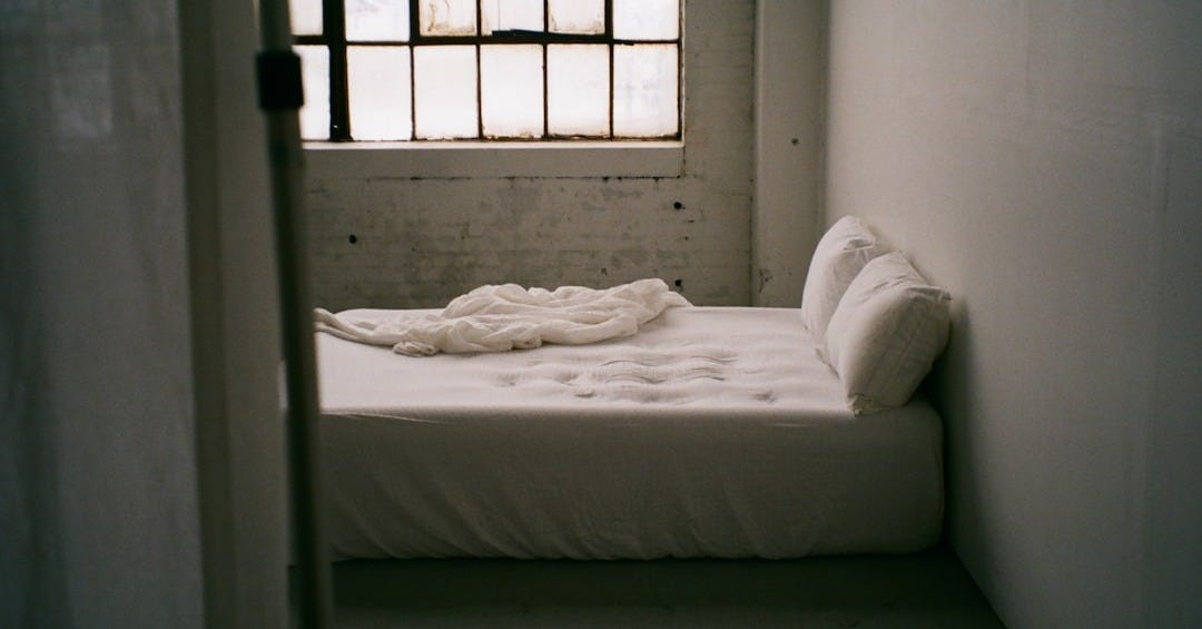 a small bed in a small room with a window a small bed in a small room with a window