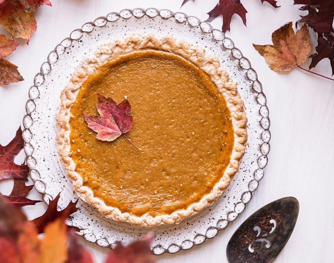 a pie sitting on top of a white table next to leaves