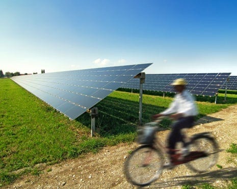 A blurry picture of a cyclist riding past solar panels. A blurry picture of a cyclist riding past solar panels.